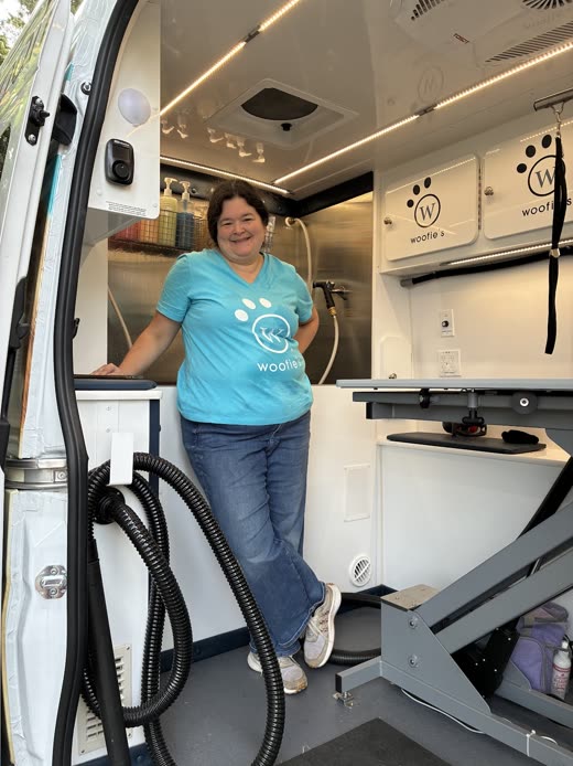 Woofie's groomer at the open door of the fitted mobile pet spa van